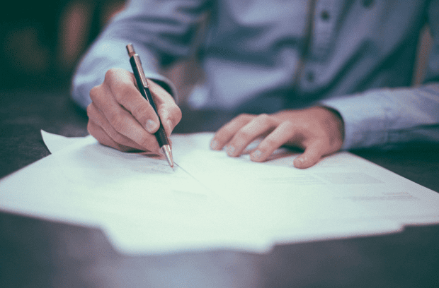 closeup shot of a person signing a document